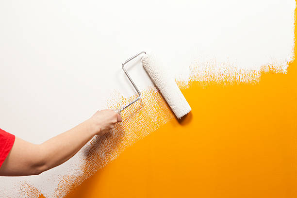 pintor virar de tinta branca sobre velha parede laranja - laranja cores imagens e fotografias de stock
