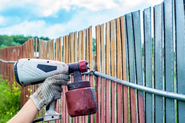 Painting metal fence spray. Man paints a fence with a paint sprayer. painting the fence to protect against corrosion Painting metal fence spray. Man paints a fence with a paint sprayer. painting the fence to protect against corrosion rusty fence stock pictures, royalty-free photos & images