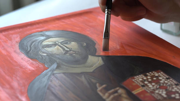 Painting Religious Icon Close up shot of a painter adding finishing layers to the religious icon painting. She is using a brush to add final strokes to the painting of a Jesus Christ Pantocrator. orthodox church stock pictures, royalty-free photos & images