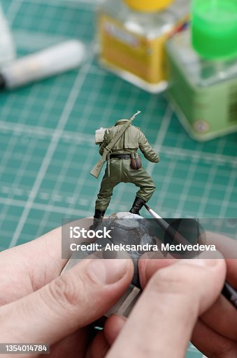 istock Painting shoes on a plastic model of a soldier close up. 1354014784