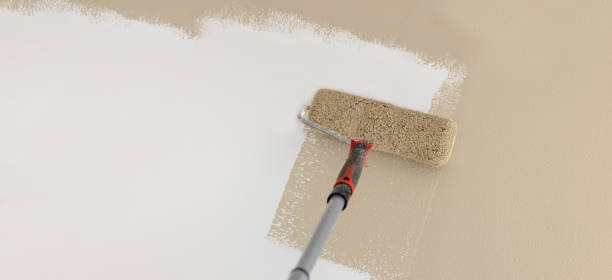 painting wall in mocha beige color with paint roller. banner copy space stock photo