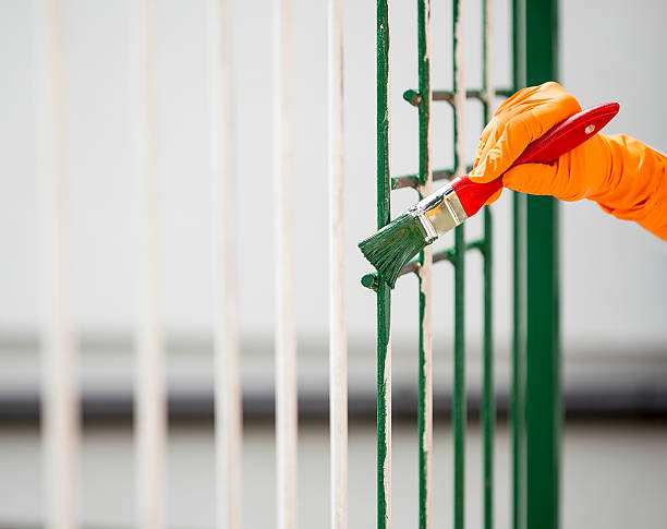 Painting with a paint brush Hand wearing orange gloves and painting with a paint brush. rusty fence stock pictures, royalty-free photos & images