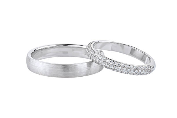 Pair of silver wedding rings isolated on white background Pair of silver wedding rings isolated on white background. White gold ring bands with diamonds on female ring and matte textured surface on male ring couple wedding ring set gold stock pictures, royalty-free photos & images