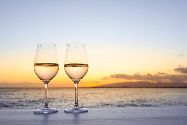 pair of wine glasses on the beach. - sunset dining stockfoto's en -beelden