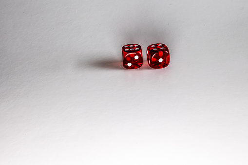A Pair of Crystal Clear Red Dice being lit from the side on a white Background.