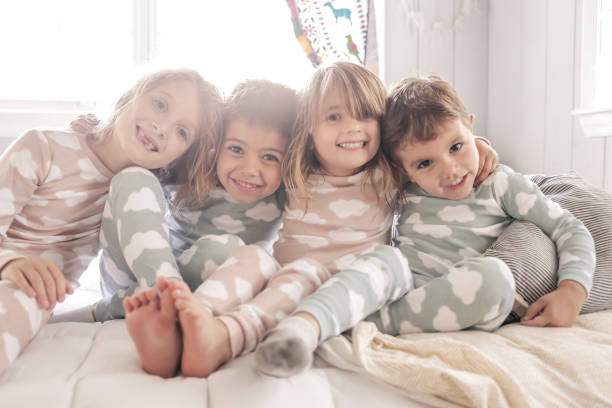 Pajama Party 4 young children smile and goof around for a group picture in their pajamas symmetry stock pictures, royalty-free photos & images