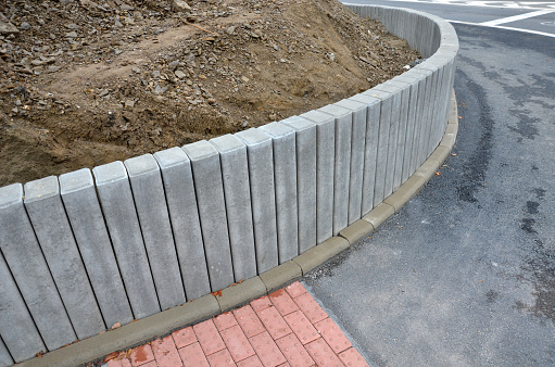 Palisades made of square-profile concrete with sloping staircase arches in garden architecture. solution of smaller terrain differences, support of slopes for edging raised flower beds on the construction site, terrain, slope, retaining wall, bump, bumps, red, gray, separation