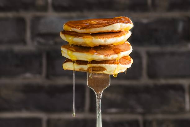 pancake con miele liquido su sfondo mattone. messa a fuoco selettiva. - pancake foto e immagini stock