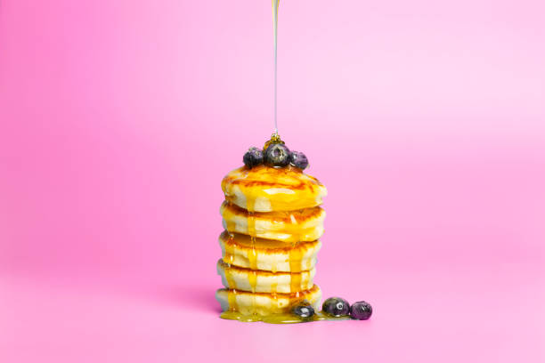 Pancakes with berries on a pink banner background. Lush delicious pancakes with blueberries and syrup for brunch on a minimal colored background. Beautiful bright food photo stock photo
