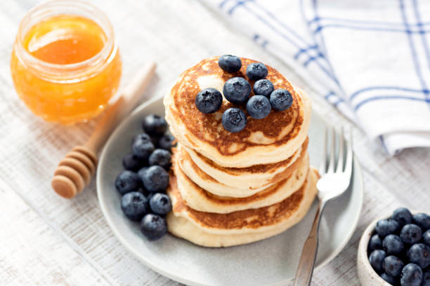 Pancakes with blueberries and honey Pancakes with blueberries and honey on white wooden table. Stack of fluffy american buttermilk pancakes. Tasty breakfast comfort food stock pictures, royalty-free photos & images