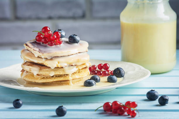 Pancakes with condensed milk are decorated with berries. Tasty breakfast. stock photo