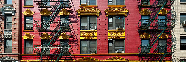 Panorama of red and yellow brick apartment building in Chinatown Brightly painted red and yellow building in Chinatown in New York City, in panoramic format. chinatown stock pictures, royalty-free photos & images