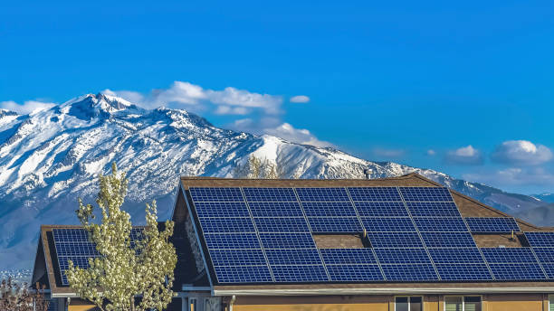 Panorama Solar panels installed on the roof of home against snowy mountain and blue sky stock photo