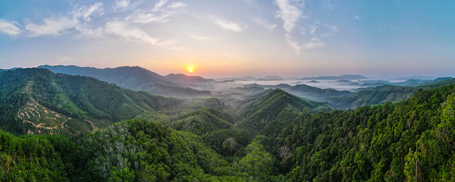 Panoramic landscape view of sunrise or sunset over mountain and misty.