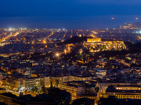 Panoramic night view of Athens and Acropolis hill at dusk. Iconic view from Hill of Lycabettus, night city light up, Acropolis hill and gulf waters.