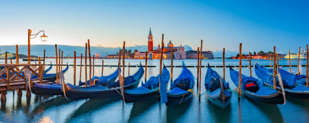 Panoramic View of Moored Gondolas and San Giorgio Maggiore at Sunrise in Venice Italy. stock photo