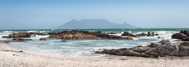 Panoramic view of Table Mountain with beach, ocean and rocks in foreground stock photo