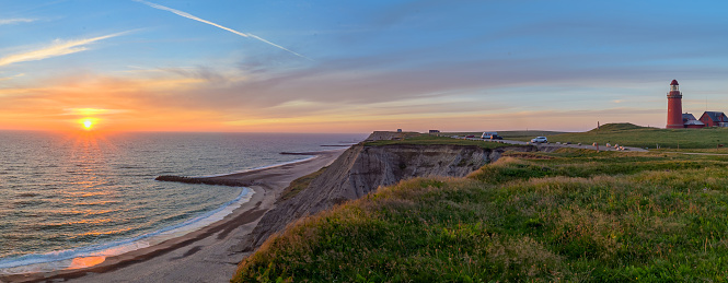 Panoramic view of the cliffs at the danish coast with the red lighthouse Bovbjerg Fyr. Panoramic view of beautiful nature landscape at the Danish North Sea coast, Jutland, Denmark, Europe.