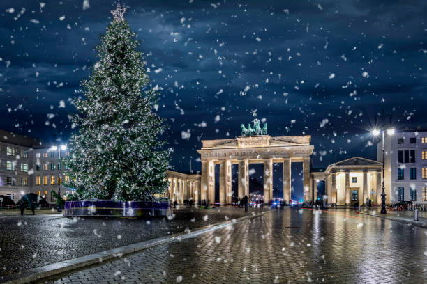 panoramisch uitzicht op de beroemde brandenburger tor in berlijn, duitsland, met een verlichte kerstboom - berlin snow stockfoto's en -beelden