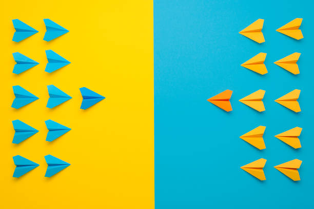 Paper airplane in battle formation. Team work concept Paper airplanes teamed up in 2 colors, blue and yellow, face to face in battle formation. A confrontation between two teams, leading the team concept. symmetry stock pictures, royalty-free photos & images