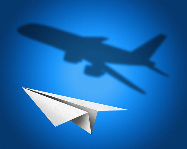 Paper airplane with a shadow of jetliner stock photo