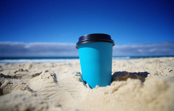 Paper coffee cup in the sand at the beach stock photo