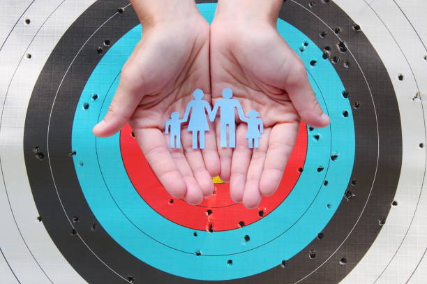 Paper family in hands on archery target background stock photo