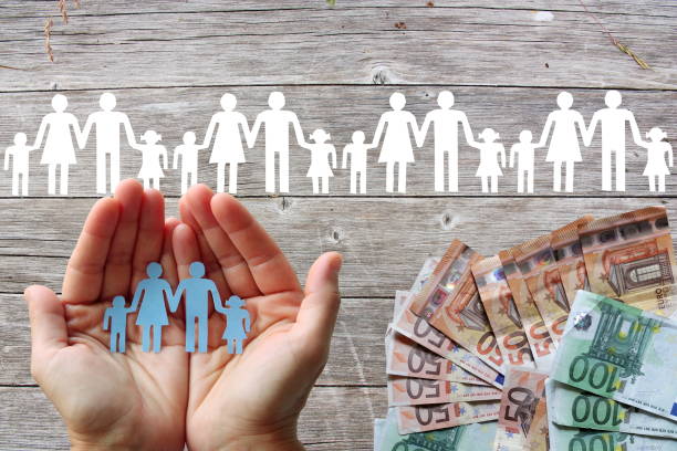 Paper family in hands on wooden background with white families and euro banknotes stock photo