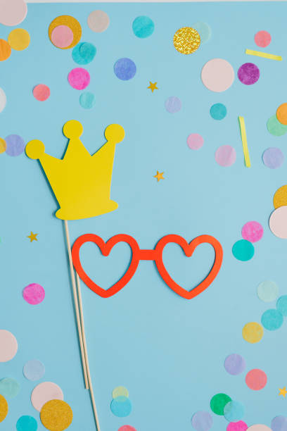 paper heart shaped eye glasses with multicolored confetti on blue background - carnival accessories flat lay imagens e fotografias de stock
