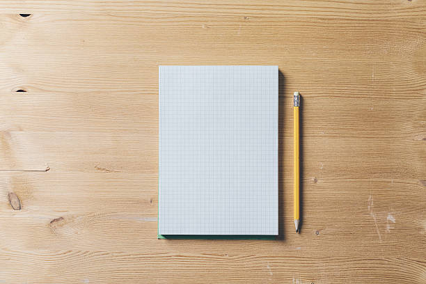 Paper notebook with pencil on a white wood table stock photo