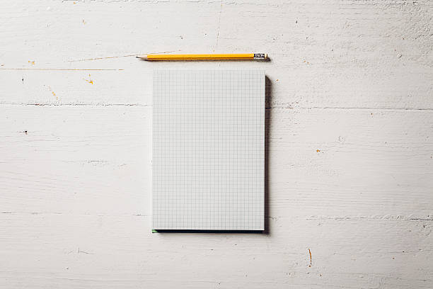 Paper notebook with pencil on a white wood table stock photo