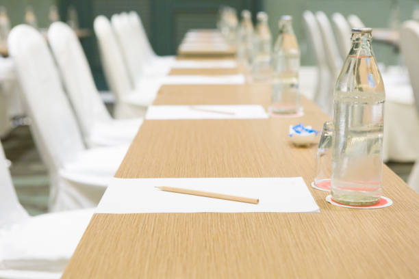 Paper, pencil, water bottle, glass on the table in the seminar room background stock photo