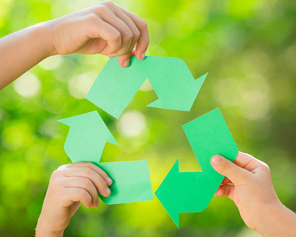 Paper RECYCLE sign in children`s hands stock photo
