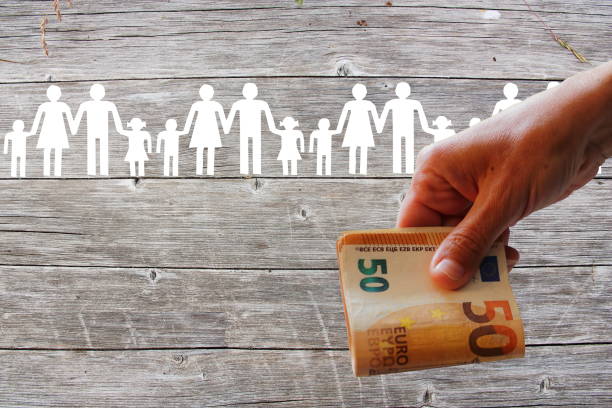 Paper white families on wooden background with Euros in hand stock photo