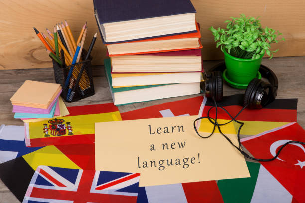 paper with text "Learn a new language!", flags, books, headphones, pencils stock photo
