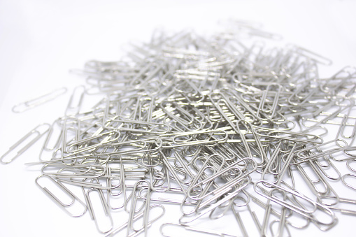 office equipment On a white background, Silver Paper Clips isolated on a textured White background
