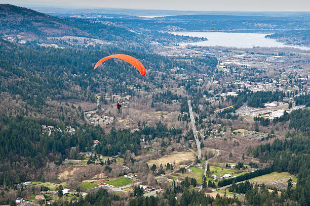 Paraglider Soaring Above Town Tiger Mountain State Forest, Washington, USA - March 07, 2012: A paraglider soars above the town of Issaquah. jeff goulden paragliding stock pictures, royalty-free photos & images