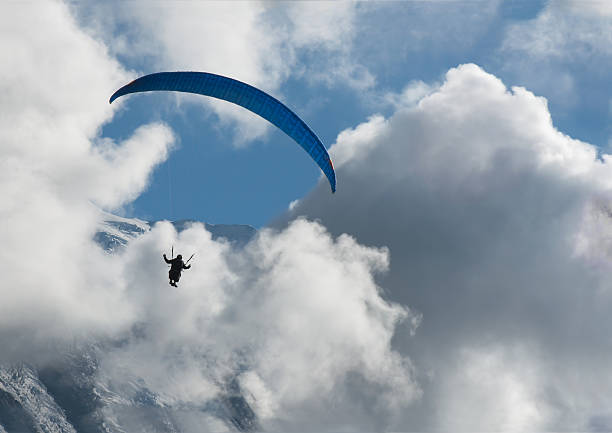 Paraglider sport parachute flying against clouds and glacier stock photo