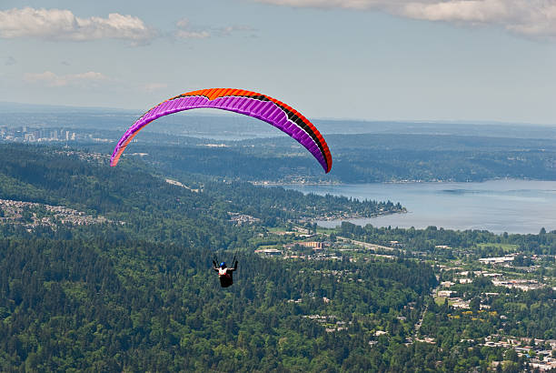 Paragliding Toward Lake Sammamish Tiger Mountain State Forest, Washington, USA - May 09, 2016: Poo Poo Point is a popular paragliding spot on Tiger Mountain in the Cascade Foothills near Issaquah. This paraglider is flying high toward Lake Sammamish in the distance. jeff goulden washington state stock pictures, royalty-free photos & images