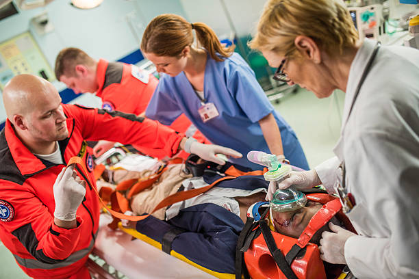 Paramedics and doctors in emergency room Paramedics, female doctor and nurse with injured patient in emergency room. accidents and disasters photos stock pictures, royalty-free photos & images