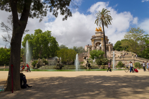 Barcelona, Spain - May 2, 2014: This image was taken in Parc de la Ciutadella, Barcelona. It shows one of the main attractions of the park, namely the monumental fountain that sits in the middle of the park. The image was taken from a bench, under a tree. The park is frequented by a lot of locals and some of them can be seen in the image.