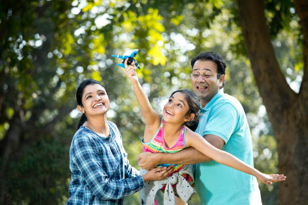 Parents with daughter flying toy airplane Parents lifting daughter helping her fly toy model airplane india photos stock pictures, royalty-free photos & images