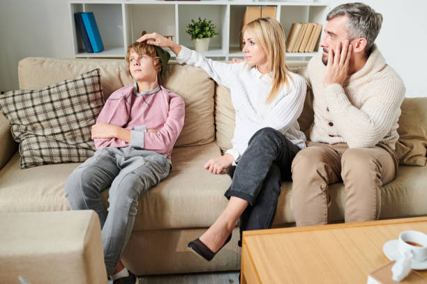 Parents worrying about teenage son Sad worried parents in casual outfit puzzled about depression of teenage son who ignoring them, disappointed mother stroking head of son in living room mother and teenage son stock pictures, royalty-free photos & images