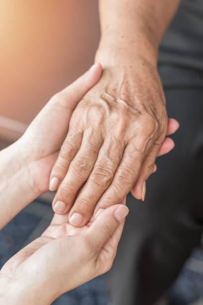 parkinson disease patient, alzheimer elderly senior, arthritis person's hand in support of nursing family caregiver care for disability awareness day, national care givers month, ageing society - grandparents vertical imagens e fotografias de stock