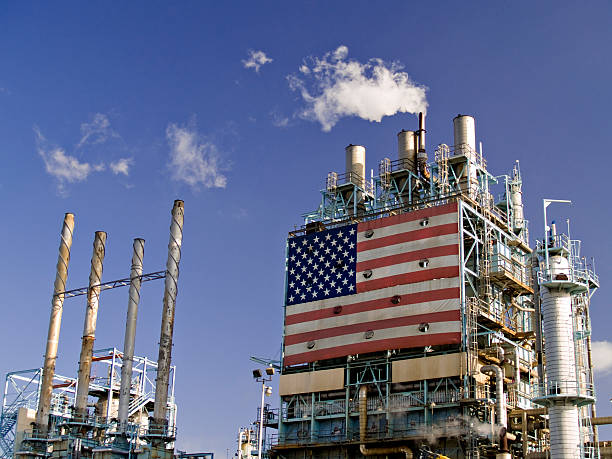Part of Refinery Complex Part of oil refinery complex with big american flag displayed. Fumes coming out from the chimney. oil refinery stock pictures, royalty-free photos & images
