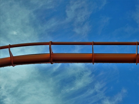Partial view of a ferris wheel arc against a blue sky