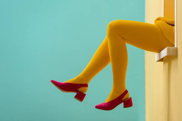 gedeeltelijke weergave van vrouw in gele panty's en roze schoenen op blauwe achtergrond - panty stockfoto's en -beelden