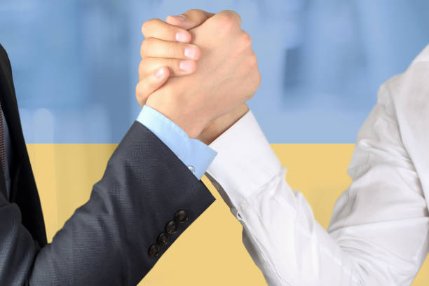 Partners shaking hands. Military Negotiations. Ukraine flag is behind. War with Russia Business patners pushing hands in fight. Ukraine flag  is behind.Partners shaking hands. Military Negotiations. Ukraine flag is behind. War with Russia rich strike stock pictures, royalty-free photos & images