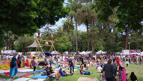 View of a public park in Santa Barbara with big crowds celebrating summer solstice after the traditional yearly parade with hundreds of dancers and performers