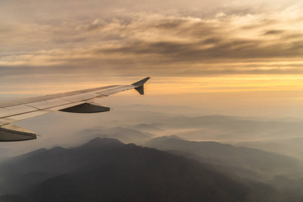 POV Passenger seat view with airplane wing and mountain in the evening stock photo